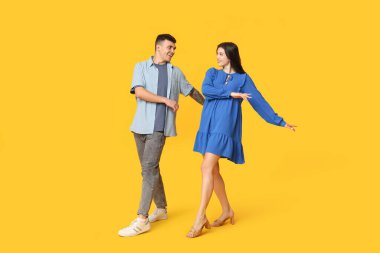 Güzel genç çift sarı arka plan üzerinde dans