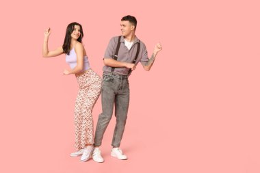 Mutlu genç çift pembe arka planda dans ediyor