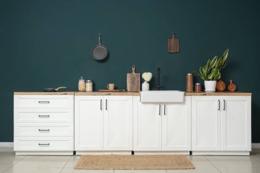 Beyaz tezgahlı, çatal bıçaklı ve lavabolu modern mutfak.