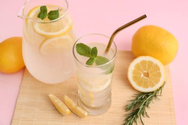 Bir bardak taze limonata ve pembe arka planda nane şekeri.