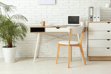 Çalışma yeri, dizüstü bilgisayarı, sandalyesi ve çekmeceleri olan şık bir ofis.