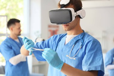 Klinikte VR gözlüğü kullanan makaslı bir erkek doktor.