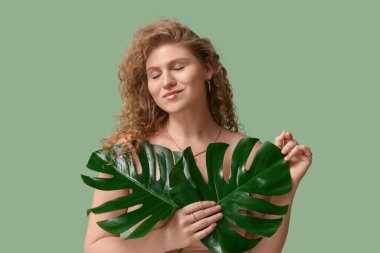 Yeşil arka planda tropikal canavar yaprakları olan güzel genç bir kadın.