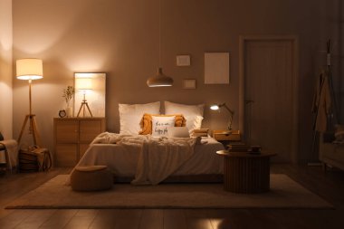 Karanlık yatak odasının içinde gece lambaları, dizüstü bilgisayarı ve kitapları vardı.