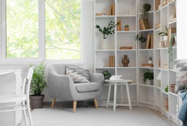 Kitaplık, koltuk ve sehpa modern oda içinde.