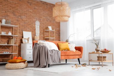 Sıcak kanepe, sonbahar dekorlu kahve masası ve oturma odasının içinde yapraklar.