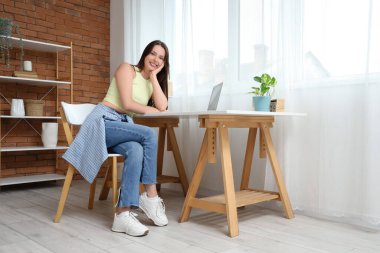 Masanın yanında oturan genç bir kadın.