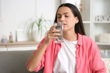 Evdeki kanepede Chia tohumu suyu içen genç bir kadın.