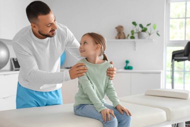 Rehabilitasyon merkezinde kanepede oturan fizyoterapisti olan tatlı küçük kız.