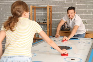 Genç adam ve arkadaşı evde hokey oynuyorlar.