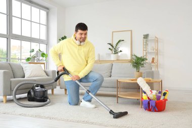 Genç adam odayı süpürüyor.