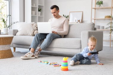 Babası evde cep telefonuyla oynarken çalışıyor.