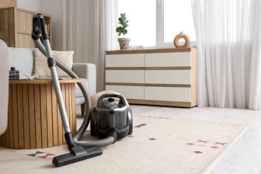 Oturma odasındaki masanın yanındaki modern elektrikli süpürge.