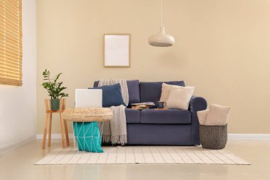 Oturma odasının iç tarafında dizüstü bilgisayarı olan rahat bir kanepe ve kahve masası.