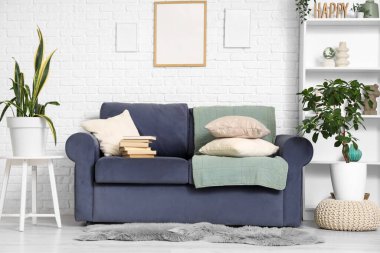 Oturma odasının iç tarafında kitap ve çiçeklerle dolu rahat bir kanepe.