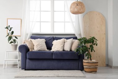 Oturma odasının iç tarafında rahat bir kanepe ve çiçek var.