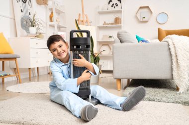 Evde pijamalı yakışıklı bir çocuk elektrikli ısıtıcıya sarılıyor.