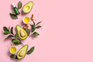 Taze avokadolu kompozisyon, pembe arka planda bir kase yağ ve bitki dalı.