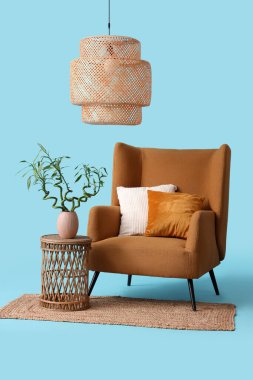 Vazoda bambu saplı masa, koltuk, halı ve lamba mavi arka planda.