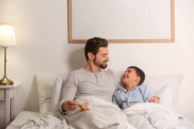 Oyuncak uçakla babası ve küçük oğlu yatak odasında yatıyor.