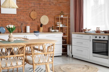 Tezgahları, raf ünitesi ve yemek masası olan modern mutfağın içi.