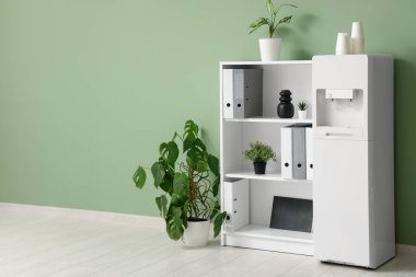 Modern su soğutucusu, ev bitkileri ve raf ünitesi olan şık bir ofis.