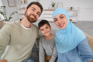 Mutlu Müslüman aile evde selfie çekiyor.