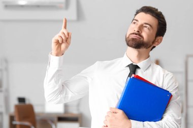 Dosyaları ofisteki bir şeyi gösteren genç işadamı.