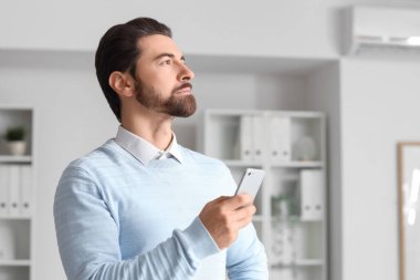 Cep telefonlu genç işadamı ofisinden yukarı bakıyor.