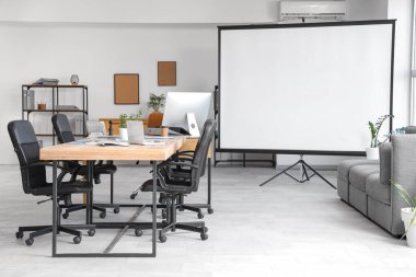 Masa ve projektör ekranlı konferans salonunun içi
