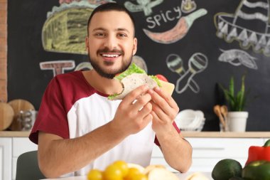 Genç adam evde lezzetli taco yiyor.