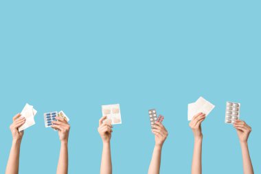 Hardal alçılı kadın elleri ve mavi arka planda haplar.