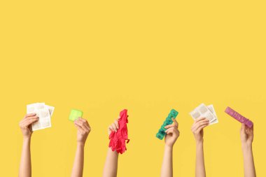 Hardal alçılı kadın elleri, ilaç kutuları ve sarı arka planda eldivenler.