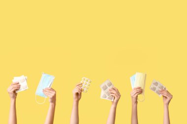 Sarı arka planda hardal sıva, hap ve tıbbi maskeli kadın elleri.