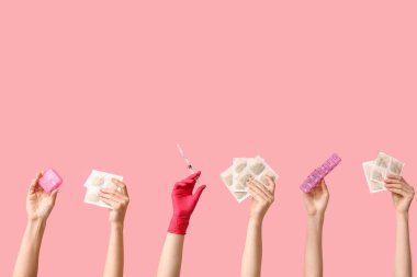 Hardal sıva, ilaç kutusu ve pembe arka planda şırınga olan kadın elleri.