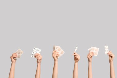 Gri arka planda hardal alçılı, haplı ve termometresi olan kadın elleri