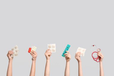 Hardal sıva, hap, steteskop ve gri arka planda ilaç kutuları olan kadın elleri.