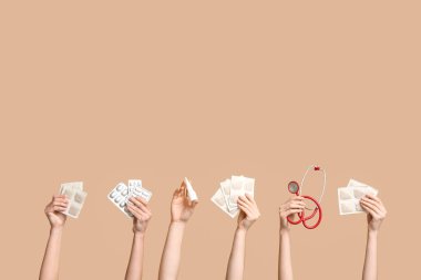 Hardal sıva, hap, steteskop ve bej arka planda burun spreyi olan kadın elleri.