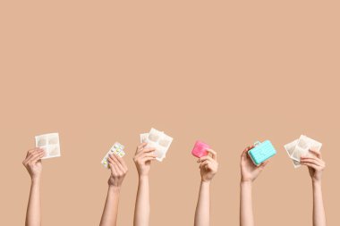 Hardal alçılı kadın elleri, ilaç kutuları ve bej arka planda haplar.