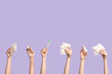 Mor arka planda hardal alçılı, termometre ve burun spreyli kadın elleri.