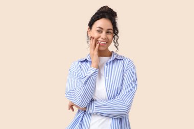 Bej arka planda sağlıklı dişleri olan gülümseyen Afro-Amerikan kadın.