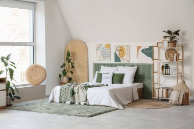 Işıklı yatak odasının içinde resimler, raf ünitesi ve bitkiler var.