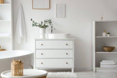 Raflar, göğüs ve çekmeceler. Lavabo, banyonun iç tarafındaki beyaz duvarın yanında.