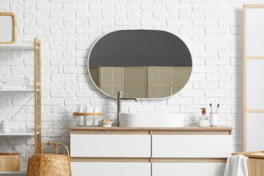 Banyodaki beyaz tuğla duvarın yanında küvet ve banyo malzemeleri olan çekmeceler.