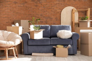 Taşındığı gün odada karton kutuları olan koltuk ve koltuk.