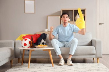 Köpük elli erkek sporcu ve evde futbol maçı izleyen Alman bayrağı.