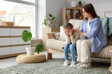 Evde baş ağrısı olan bir kadın ve küçük kızı.