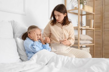 Küçük kızına evde baş ağrısı ilacı veren bir kadın.