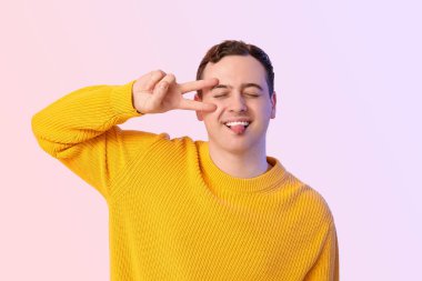 Yakışıklı, genç ve mutlu bir adam zafer jesti yapıyor.