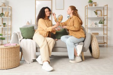 Güzel, genç, mutlu bayan arkadaşlar evde makyaj yapıyorlar.